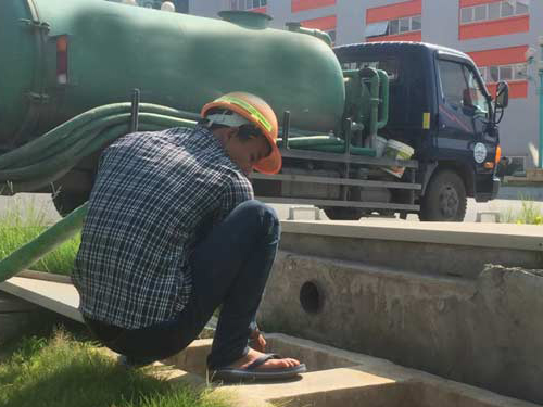 Công nhân đưa ống hút vào bể phốt